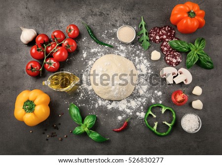 Raw dough for pizza with ingredients and spices on table