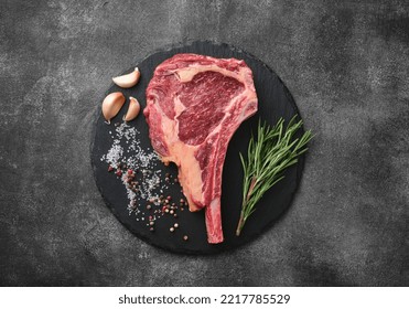 Raw dry aged beef tomahawk steak on slate board with spices for grill - Powered by Shutterstock