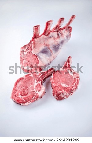 Raw dry aged bone-in back rack of veal loin offered as close-up on a black board