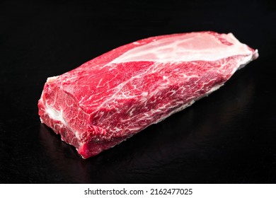 Raw dry aged wagyu beef clod roast as closeup on black background with copy space 