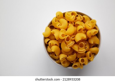 Raw Dry Organic Pipe Rigate Pasta In A Bowl On White Background, Top View. Flat Lay, Overhead, From Above. Copy Space.