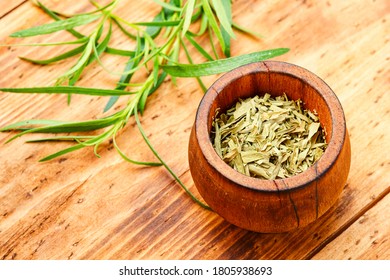 Raw and dry tarragon spice.Tarragon or Artemisia dracunculus on wooden table