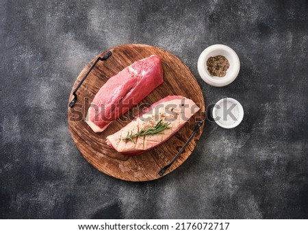 Raw duck breast with herbs and spices on a dark concrete background. Raw meat prepared for baking