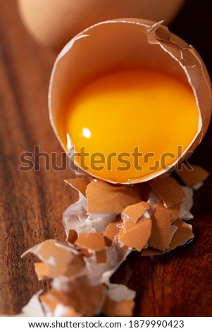 Raw egg yoke in brown shell with broken shell pieces