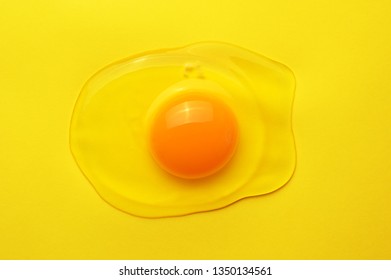 Raw Egg Yolk On The Yellow Background