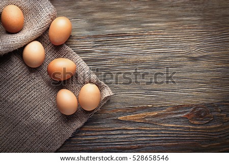 Raw eggs on sackcloth on wooden table