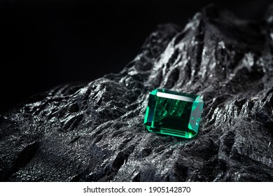 黒い石炭の背景に生のエメラルド、宝石