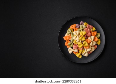 Raw farfalle pasta in different colors on a dark concrete background. Preparing to cook Italian food - Powered by Shutterstock