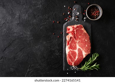 Raw fillet meat pork on board with peper seasoning and green rosemary on black background, top view, close up, copy space - Shutterstock ID 2274165141
