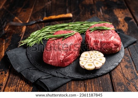 Raw Fillet Mignon Beef steak with herbs and garlic, marble meat. Wooden background. Top view.