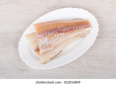 Raw Fillets Of Pollock In Plate On Wooden Table. Top View