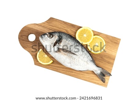 Raw fish Dorado with lemon on a wooden board isolated on a white background. Top view.