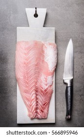 Raw Fish Fillet  On Marble Cutting Board With Kitchen Knife, Top View. Seafood Concept