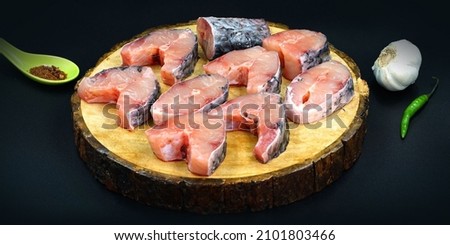 Raw fish pieces ready to be cooked and served on a platter with garlic and some spices.