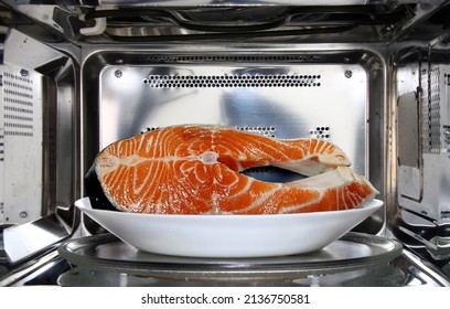 Raw fish in plate defrosting using microwave oven in close up - Powered by Shutterstock