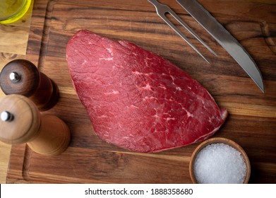 raw flank steak on wooden cutting board