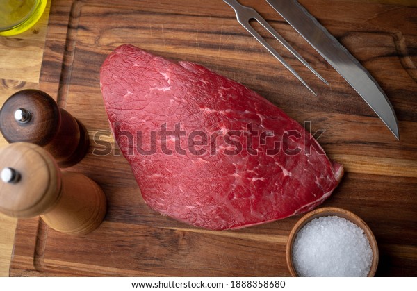 raw flank steak on\
wooden cutting board