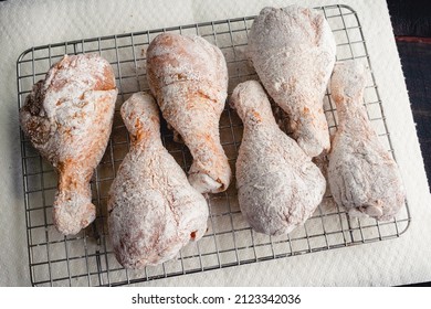 Raw Floured and Spiced Chicken Drumsticks on a Wire Rack: Floured uncooked chicken legs being prepped for frying - Shutterstock ID 2123342036