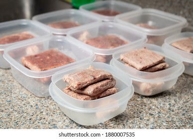 Raw Food Diet Meal Prep For Cats, Dogs Or Pets. Frozen Raw Ground Chicken And Turkey Meat Inclusive Backs, Necks, Liver And Hearts Separated In Daily Tupperware Portions For Two Cats. Selective Focus.