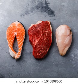 Raw Food Salmon Oily Fish Steak, Beef Meat And Chicken Breast On Gray Concrete Background