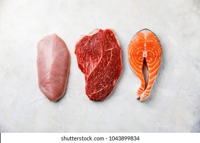 Raw food turkey breast, beef meat and Salmon oily fish steak on white textured background