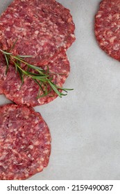 Raw Free Range 100% Beef Burger Patties On Mottled Grey With Copy Space