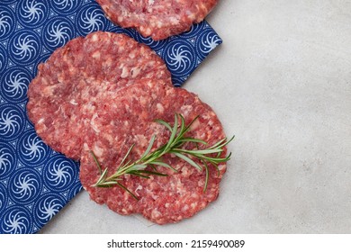 Raw Free Range 100% Beef Burger Patties On Mottled Grey With Copy Space