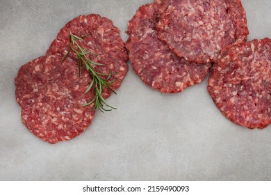 Raw Free Range 100% Beef Burger Patties On Mottled Grey With Copy Space