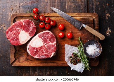 Raw fresh cross cut veal shank and seasonings for making Osso Buco on wooden cutting board
