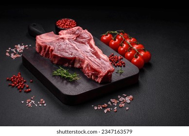 Raw fresh juicy beef t-bone steak with salt, spices and herbs on a dark concrete background - Powered by Shutterstock