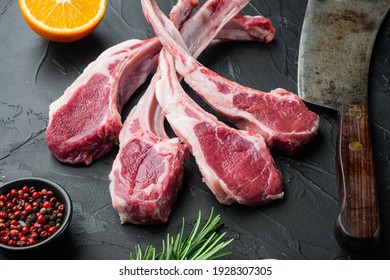 Raw fresh lamb loin chops set, with ingredients carrot orange, herbs, on black stone background