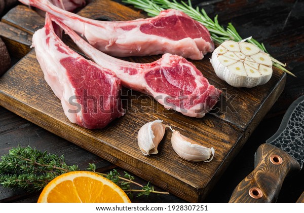 Raw fresh lamb loin\
chops set, with ingredients carrot orange, herbs, on old dark\
wooden table background