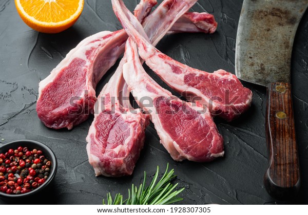 Raw fresh lamb loin chops set,\
with ingredients carrot orange, herbs, on black stone\
background