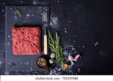 Raw fresh lamb meat and meat fork on dark background, burger patty ingredients. Top view. Free space.