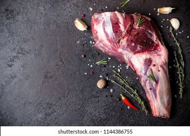 Raw fresh Lamb Meat shank and seasonings on black stone background.