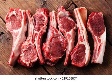 Raw fresh lamb ribs on wooden cutting board on dark background