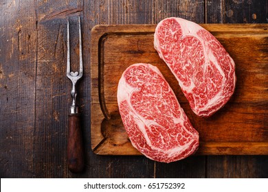 Raw fresh marbled meat Steak Ribeye Black Angus and meat fork on wooden background copy space