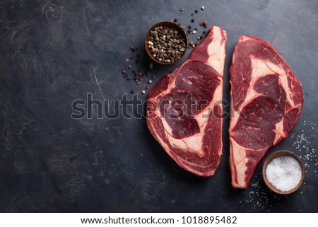 Raw fresh marbled meat Steak Ribeye Black Angus on black marble background. Beef with spices on a dark stone table. Top view with copy space