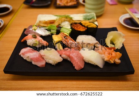 Raw and fresh Mix sushi set in black plate include Otoro (Fatty blue fins tuna), Uni (urchin), Unagi (eel), salmon and others  - Japanese food set style at Tsukiji fish market, Tokyo