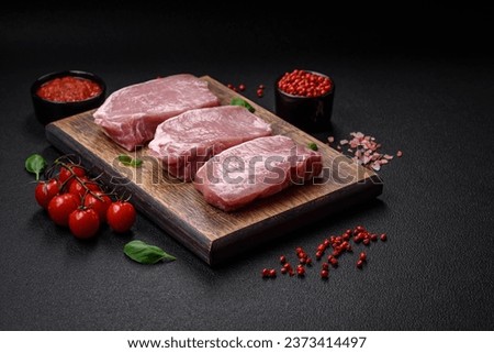 Raw fresh pork meat steak with salt, spices and herbs on a wooden cutting board