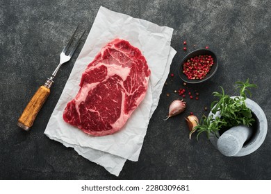 Raw fresh ribeye steak or Rib-eye steak. Raw fresh marbled meat Ribeye Black Angus and seasonings pepper, rosemary, thyme and salt on old wooden rustic background. Top view and copy space. - Powered by Shutterstock