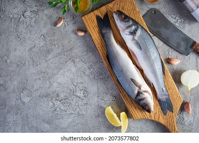 Raw fresh sea bass with different spices on cutting board. Top view