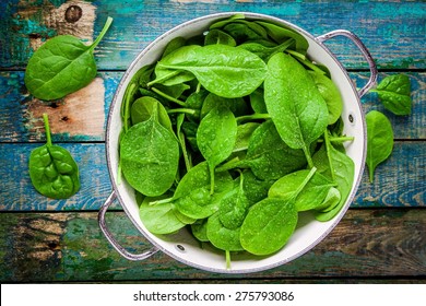 raw fresh spinach with drops in a colander on a rustic wooden table - Powered by Shutterstock