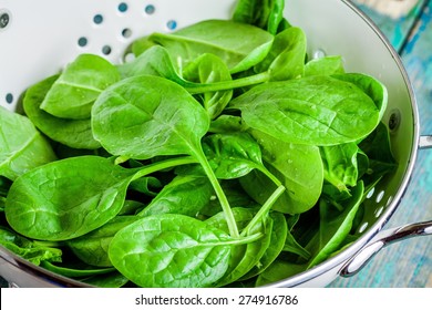 raw fresh spinach in a white colander closeup on a rustic wooden table - Powered by Shutterstock