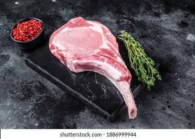 Raw Fresh Tomahawk Pork Chop Steak On A Marble Board. Black Background. Top View.