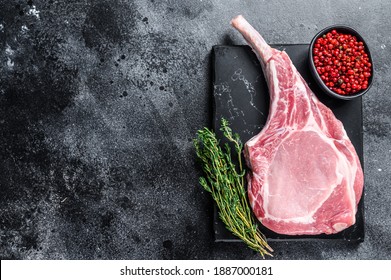 Raw Fresh Tomahawk Pork Chop Steak On A Marble Board. Black Background. Top View. Copy Space.