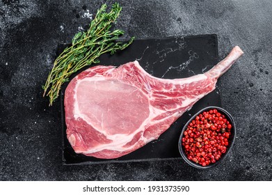 Raw Fresh Tomahawk Pork Chop Steak On A Marble Board. Black Background. Top View.