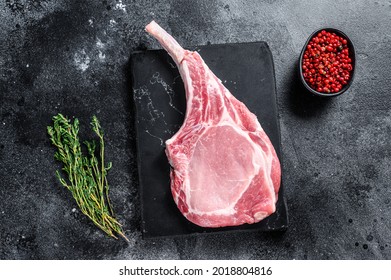 Raw Fresh Tomahawk Pork Chop Steak On A Marble Board. Black Background. Top View