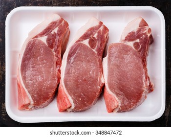 Raw fresh uncooked Pork meat chop steak on bone in white container packaging tray