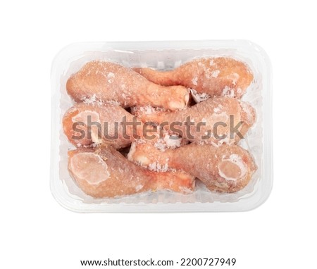 Raw frozen chicken drumsticks in a plastic container isolated. Fresh iced chicken legs, drumsticks on white background with clipping path top view